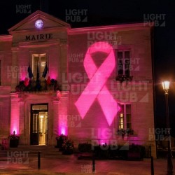 Projection d’un ruban rose lumineux sur la façade d’une mairie pour Octobre Rose